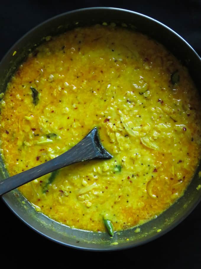 cooked dhal curry in a pan with a wooden spoon inside