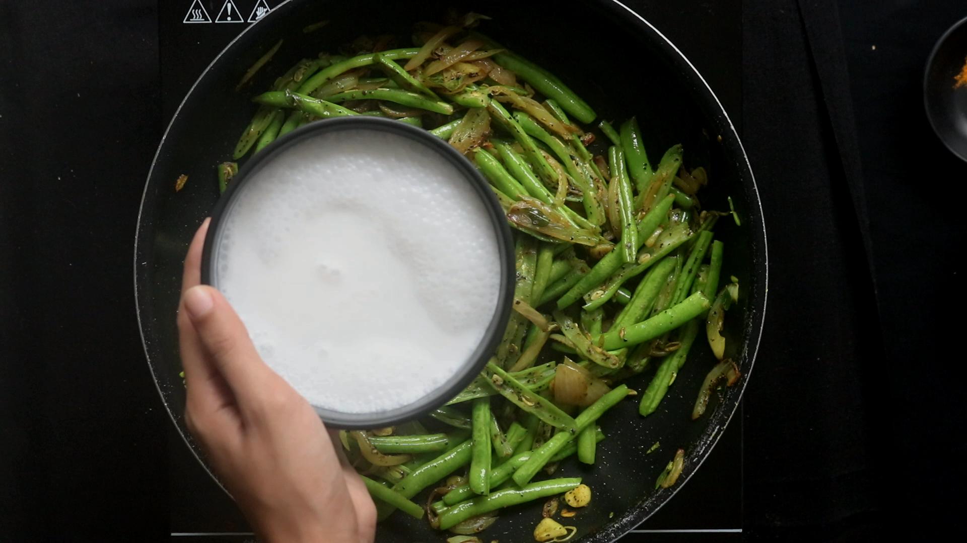 adding coconut milk for a little gravy to the beans curry