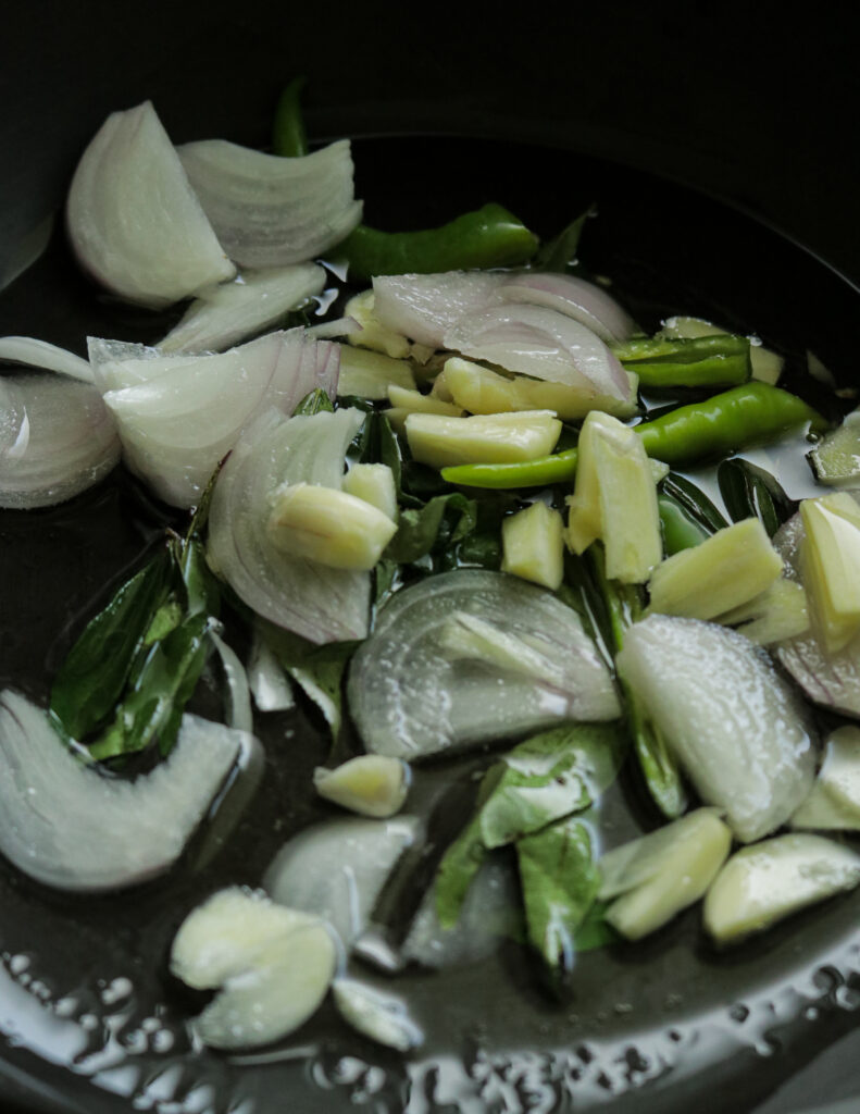 cooking the onions,curry leaves, green chillies in oil to make the egg curry