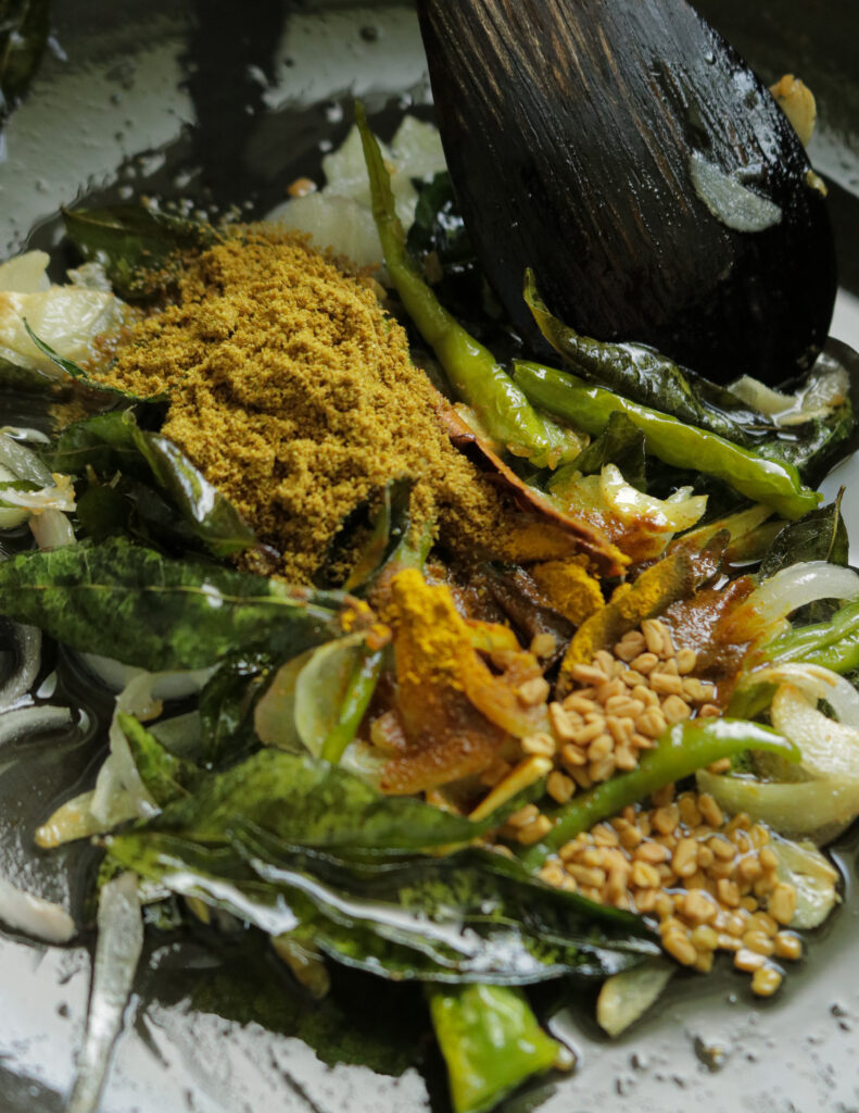 adding spices, fenugreek seeds to the tempered onions to make the egg curry.