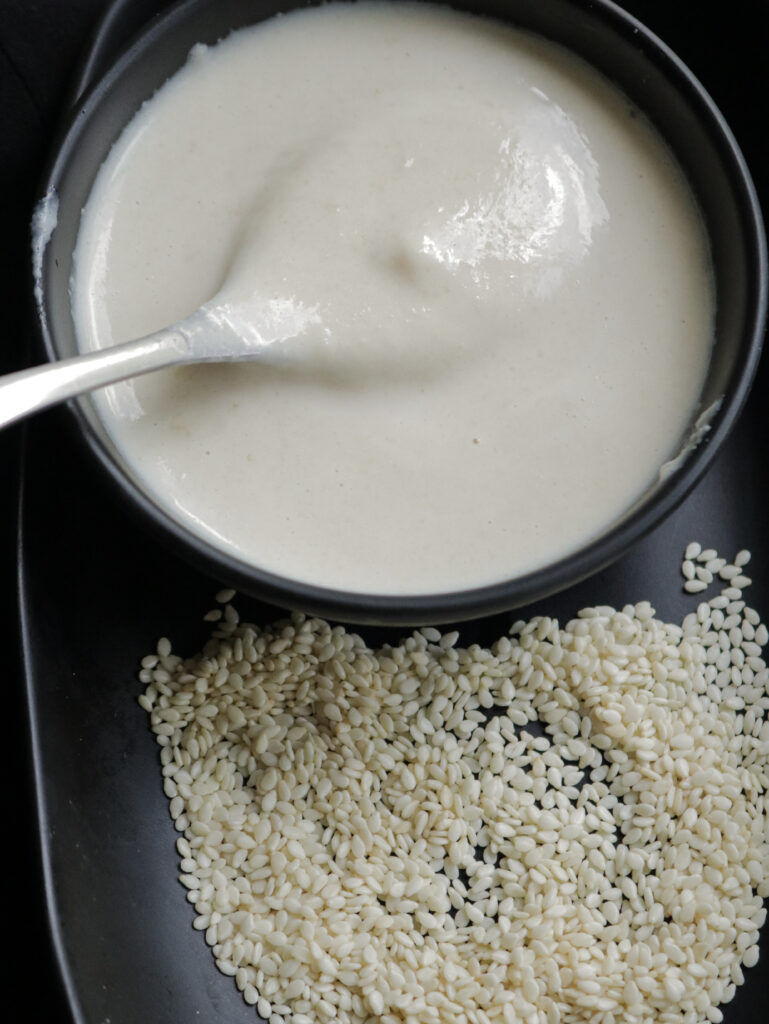 smooth tahini or homemade sesame paste mixed with a small silver spoon.