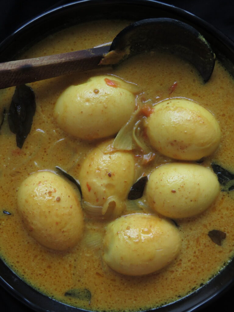 adding the boiled eggs to the coconut milk curry.