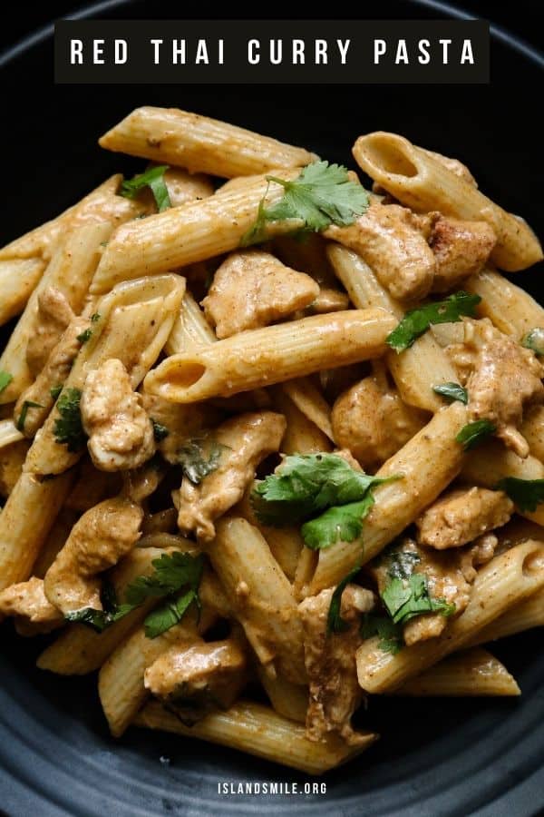 creamy thai chicken curry pasta served in a black plate with chopped coriander as garnish.
