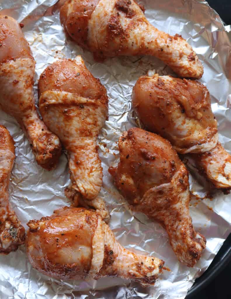 placing the skin on chicken drumsticks on top of foil to bake.