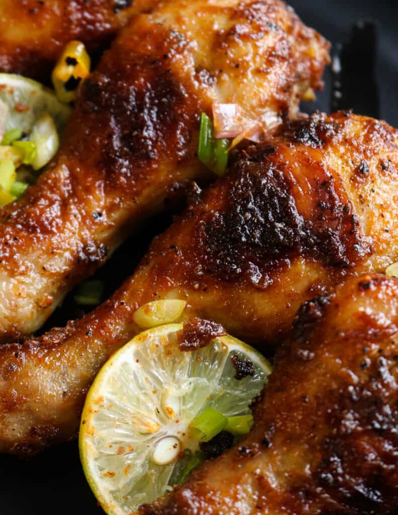 baked chicken drumsticks with slices of lime and garnishes.