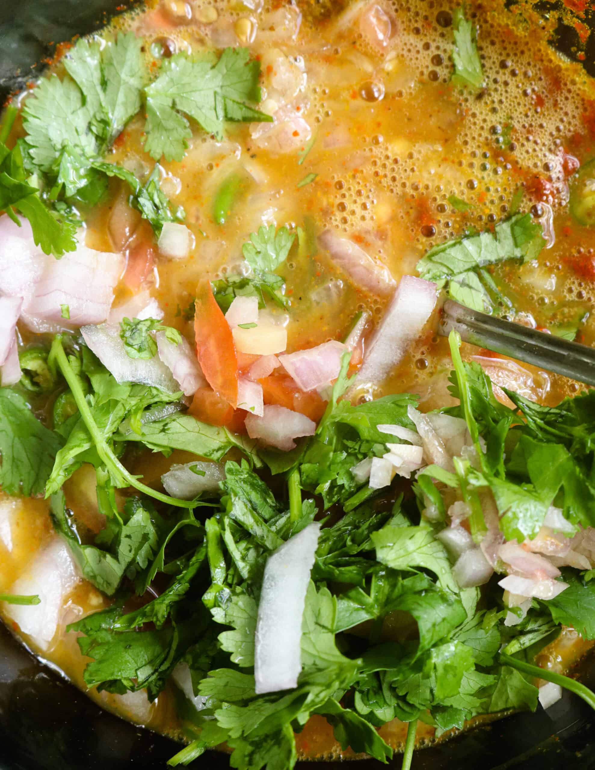 adding chopped onions, chopped tomatoes, chopped coriander and spice powders to make the masala omelette.