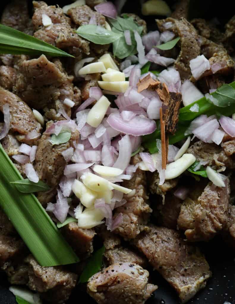 adding chopped onions, galic, pandan leaf to the cooking sliced beef.