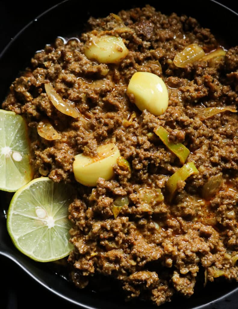 minced beef curry with garlic and onions and slices of limes.