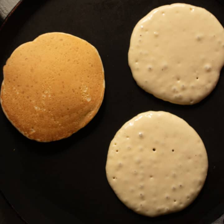 cooking american pancakes and flipping them over on the griddle.