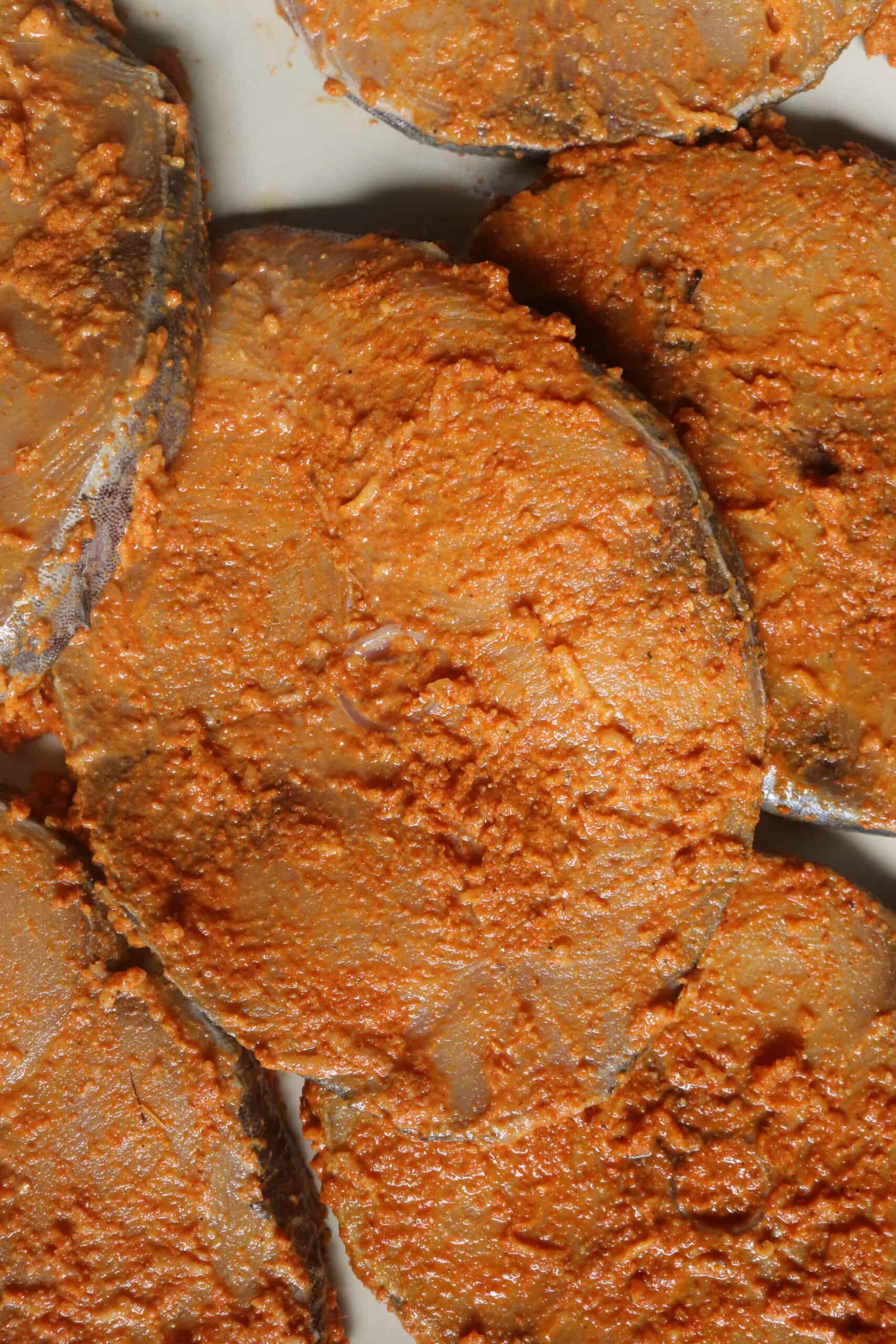 covering the fish steaks with spice masala to marinate.