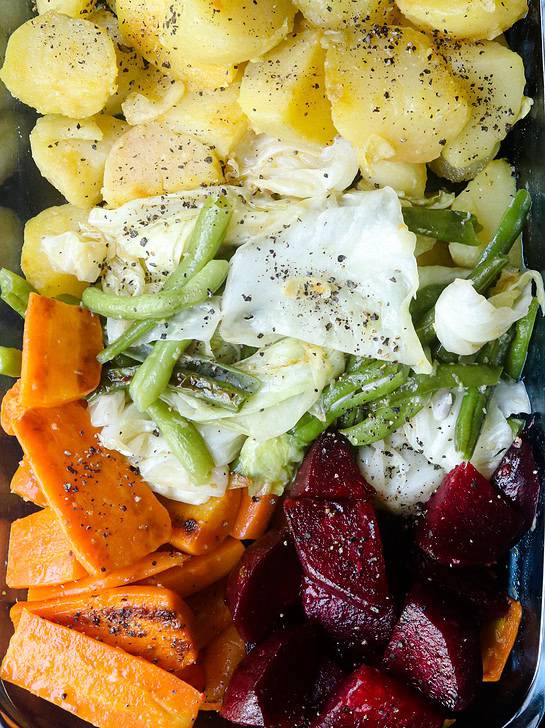 A dish of boiled potatoes, beetroot, beans, carrots and cabbages.